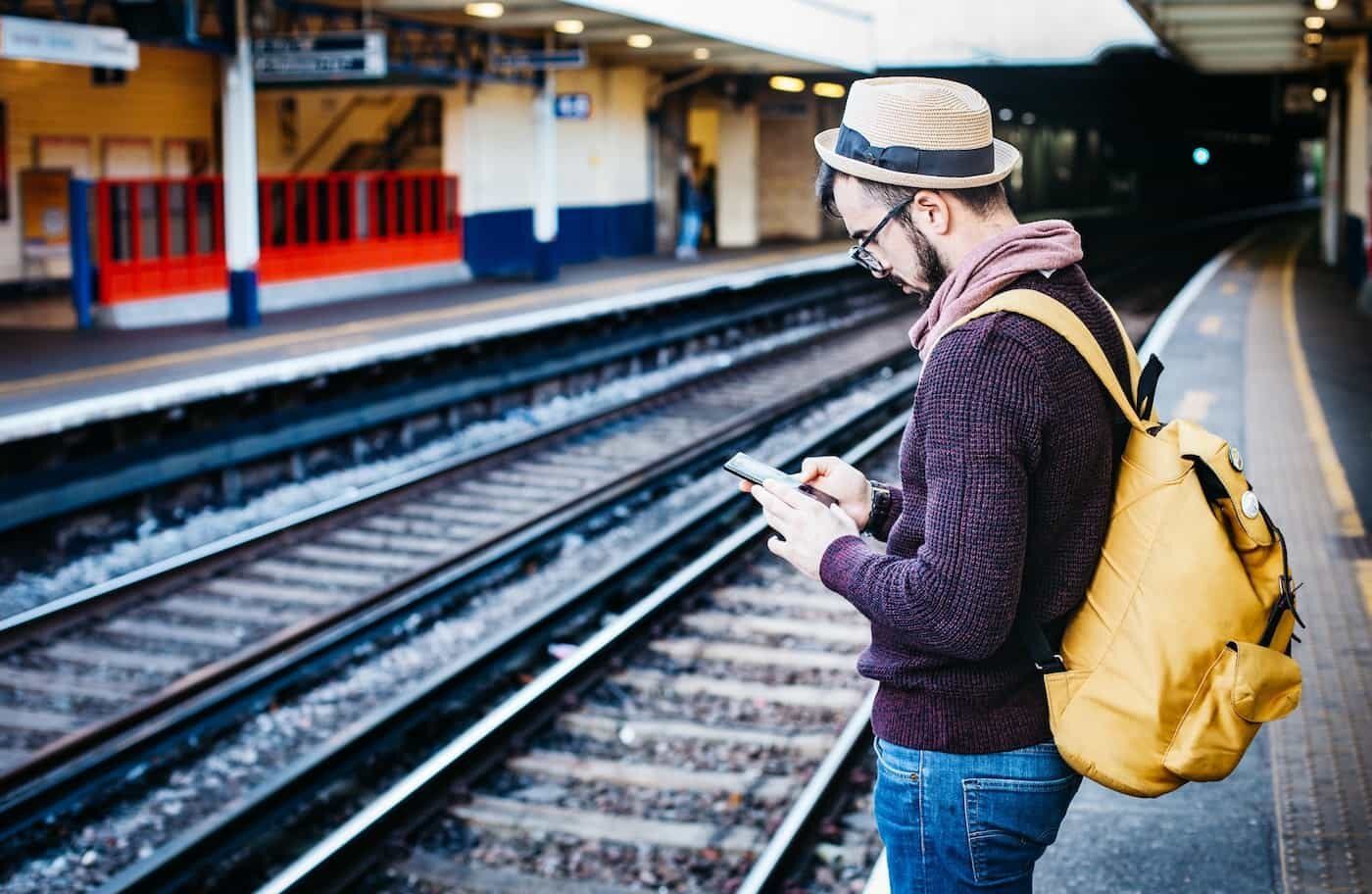 Reisender mit Rucksack am Bahngleis